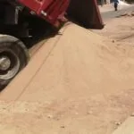 Descarga de arena fina desde camión volquete para construcción en vía urbana. venta de agregados