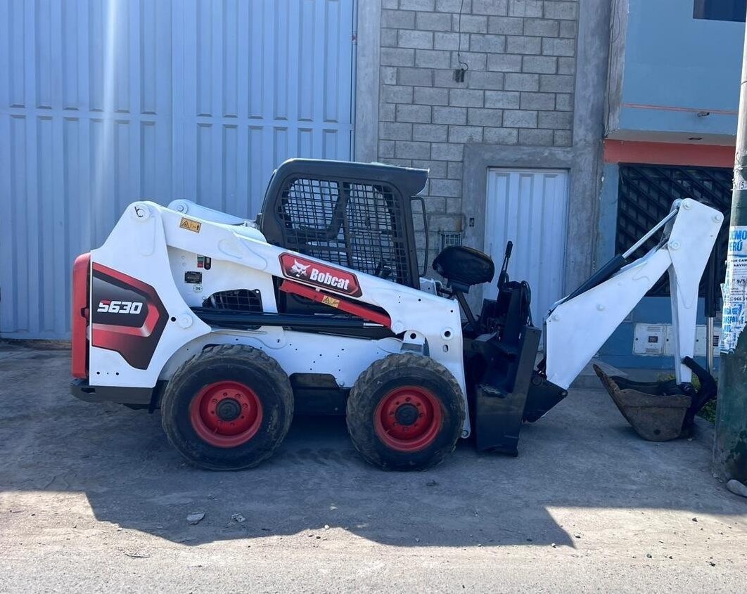 Minicargador Bobcat S630 con retroexcavadora, equipo compacto para excavaciones precisas y movimientos de tierra en espacios reducidos y entornos urbanos.