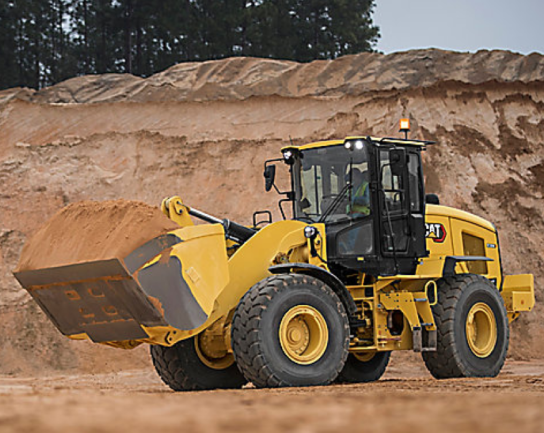 Cargador frontal CAT transportando arena en una obra de construcción.