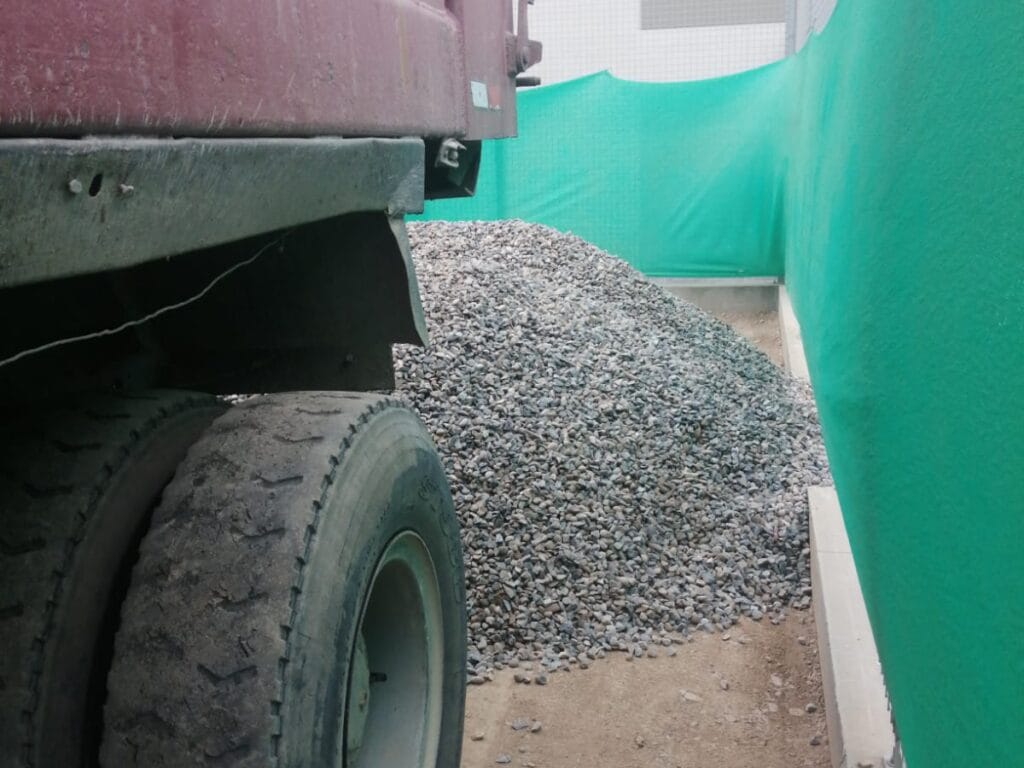 Montículo de piedra chancada descargado por volquete doble eje en almacén