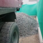 Montículo de piedra chancada descargado por volquete doble eje en almacén