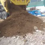 Volquete cien pies amarillo descargando tierra de chacra en obra de Lima, Perú