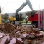 Excavadora Volvo cargando desmonte en volquete rojo para el retiro de residuos de demolición. Eliminación de desmonte